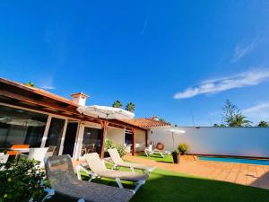 einen Hinterhof mit Stühlen, einem Sonnenschirm und einem Pool in der Unterkunft Bungalows Teresa in Playa del Ingles