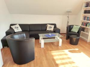ein Wohnzimmer mit einem schwarzen Sofa und einem Tisch in der Unterkunft Ferienwohnung am See, Hage / Norddeich in Hage