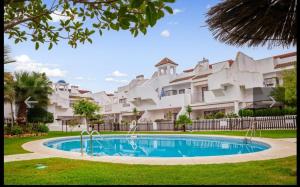 una piscina frente a un gran edificio de apartamentos en Islantilla golf playa, en Huelva