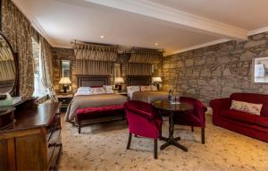a bedroom with two beds and a table and a couch at Cabra Castle Hotel in Kingscourt
