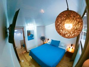 Habitación pequeña con cama azul y lámpara de araña. en Casa Jardin del Mango en San José