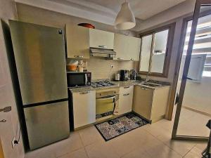 uma cozinha com armários brancos e um frigorífico de aço inoxidável em appartement moderne au style beldi résidence au centre de Marrakech avec piscine em Marrakech