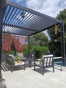a pergola with two chairs and a table next to a pool at Charmante maison avec piscine chauffée, salle de cinéma et bar in Auffargis