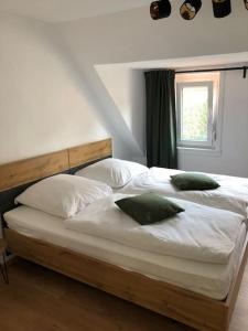 1 cama grande con sábanas blancas y almohadas verdes en 2 Zimmer Wohnung in Giessen-Mitte en Gießen