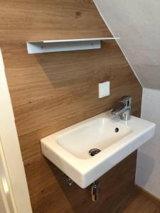 - Baño con lavabo blanco y pared de madera en 2 Zimmer Wohnung in Giessen-Mitte en Gießen