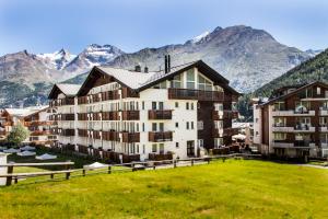 a large building with mountains in the background at Saaserhof Apartments in Saas-Fee