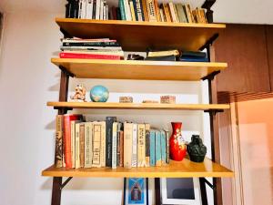 a book shelf with books and vases on it at Good apartment 2 bedroom in Bat Yam