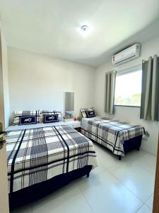 1 dormitorio con 2 camas y ventana en Lençóis Confort 201, en Barreirinhas