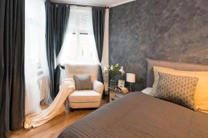 a bedroom with a bed and a chair and a window at STING Boutique Apartments in Ostrava