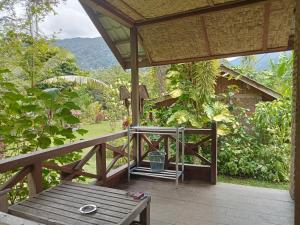 une terrasse en bois avec un banc et une table dans l'établissement Thousand hills ketambe, à Lhokuenam