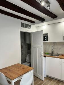 a kitchen with white cabinets and a wooden table at Belle F2 centre ville Massy avec jardin in Massy