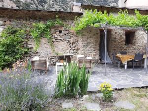 a stone building with a patio with chairs and a table at Maison traditionnelle catalane avec jardin 