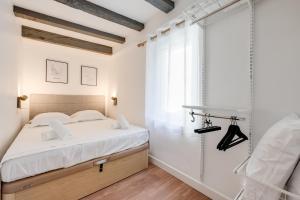 a white bedroom with a bed and a window at L'Escale bleue in Annecy