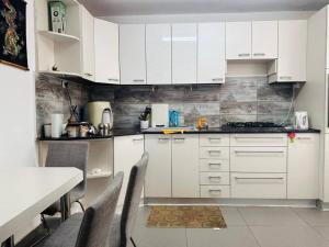 a kitchen with white cabinets and a table and chairs at Great 2 BR apartment view to the garden in Bat Yam