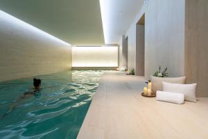 a pool of water in a room with a person in the water at Hôtel & SPA Napoléon in Fontainebleau