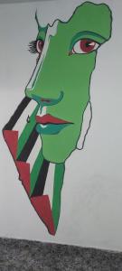 une peinture d'une grenouille verte portant une cravate dans l'établissement Jenin Hostel, à Janīn