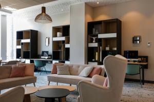 ein Wohnzimmer mit einem Sofa, Stühlen und Tischen in der Unterkunft Hilton Garden Inn Bordeaux Centre in Bordeaux