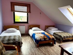 sypialnia na poddaszu z 2 łóżkami i oknem w obiekcie Pokoje PRZY SZELMENCIE w mieście Jeleniewo