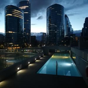 a swimming pool on top of a building with a city skyline at Hotel Los Españoles Plus in Santiago