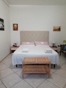 a bedroom with a large white bed with a bench at Residenza Del Sole in Surbo