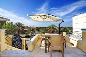 a table and chairs on a balcony with an umbrella at Garitsa Gem Suite in Corfu Town