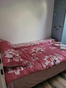 Una cama con una colcha roja con flores. en Casa Eni en Cluj-Napoca