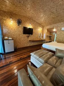 a bedroom with a bed and a couch and a tv at ธารามนตรา รีสอร์ท (Taramontra resort) in Tha Kradan