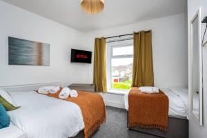 a bedroom with two beds and a window at Harvest House - TV in every bedroom! in Swansea