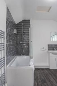 a bathroom with a bath tub with a brick wall at Harvest House - TV in every bedroom! in Swansea