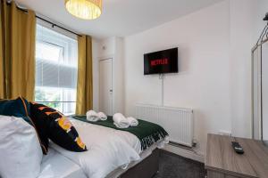1 dormitorio con 1 cama con reloj en la pared en Harvest House - TV in every bedroom! en Swansea