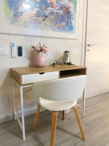 un escritorio con una silla blanca y un jarrón de flores en Relais Delta Bed Breakfast, 