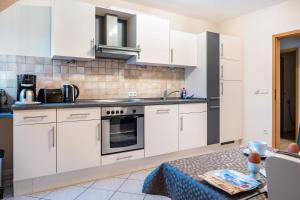 a kitchen with white cabinets and a sink and a table at Ferienwohnung Heimathafen in Cuxhaven