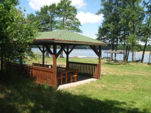 a wooden gazebo in a park with the beach at Nad Zatoką pokoje z widokiem na jezioro in Ryn