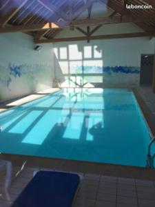 a large swimming pool with blue water in a building at APPARTEMENT PIEDS DE PISTE - 4-6 PERSONNES in La Chal