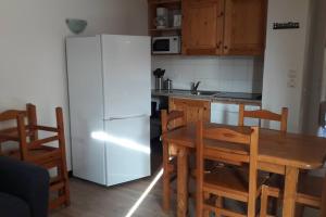 a kitchen with a table and a white refrigerator at APPARTEMENT PIEDS DE PISTE - 4-6 PERSONNES in La Chal