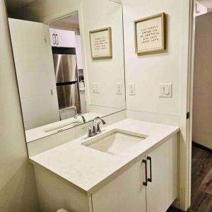 a white bathroom with a sink and a mirror at Cozy 1 Bedroom Basement Apt in SE Calgary in Calgary