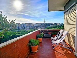 balcón con 2 sillas blancas y macetas en Terraced Park View Penthouse, en Roma