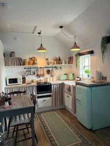 a kitchen with a stove and a table with chairs at The Nest Quaint Luxury Cottage Getaway in Tiragarvan