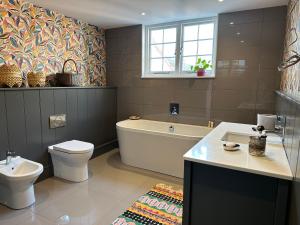 a bathroom with a tub and a toilet and a sink at The Priory 