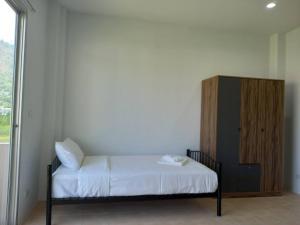 - une chambre avec un lit et une armoire en bois dans l'établissement L&P Guesthouse, à Kata Beach