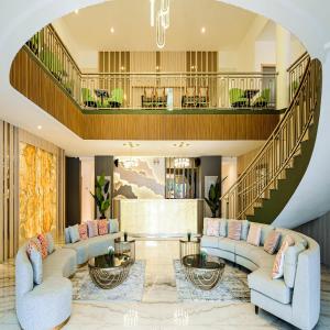 a living room with couches and a staircase at Yulia Hotel Managed by HIG in Gorontalo