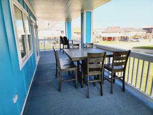 una mesa de madera y sillas en un porche en Acapulco - Upstairs Beachview Beauty 50 steps to a private beach! BYOT en Galveston