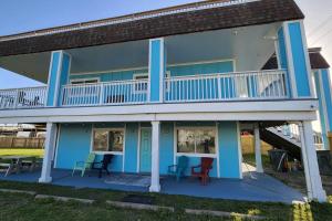 a blue house with chairs and a balcony at Acapulco - Upstairs Beachview Beauty 50 steps to a private beach! BYOT in Galveston
