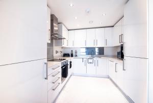 uma cozinha branca com armários brancos e um lavatório em Top Floor Apt - 2 Bed/2 Bath + Private Balcony em Londres