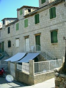 a building with a blue awning in front of it at Marina Rooms in Komiža
