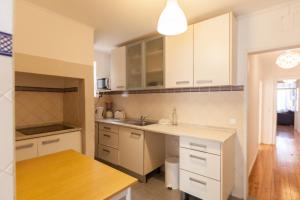 a kitchen with white cabinets and a wooden table at FLH - Central Flat in Bairro Alto in Lisbon