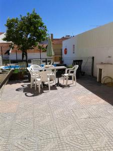 un patio con mesa, sillas y un árbol en 3 bedrooms apartement with city view shared pool and enclosed garden at Feijo 5 km away from the beach en Almada