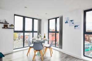 a dining room with windows and a table and chairs at Stylish 2 Bed Apartment with Free parking, close to City Centre by Hass Haus in Manchester