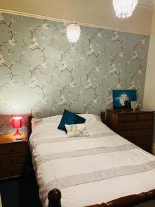 a bedroom with a bed and a wall with wallpaper at Westbrook-Homestay in Swansea