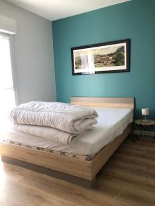 Un dormitorio con una cama con una pared azul. en maison 400 m de la plage, en Barneville-Carteret